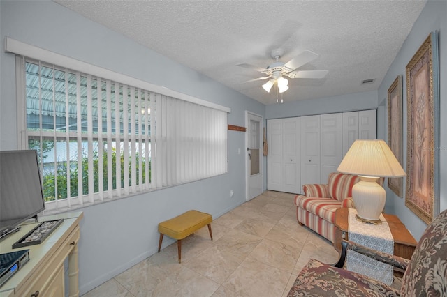 living area with a textured ceiling and ceiling fan