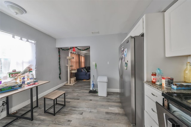 kitchen featuring appliances with stainless steel finishes, light hardwood / wood-style floors, white cabinetry, and dark stone countertops