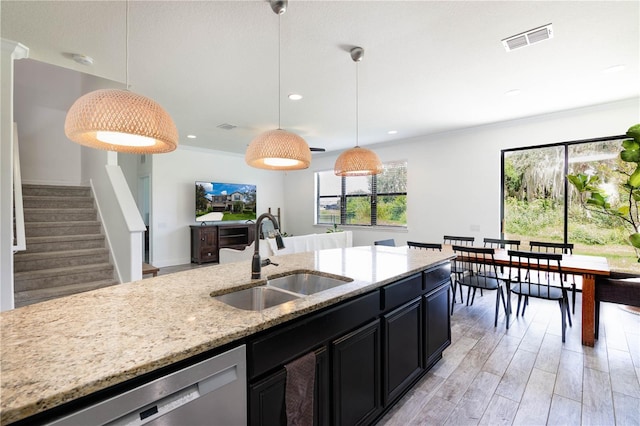 kitchen featuring light stone countertops, light hardwood / wood-style floors, hanging light fixtures, and sink