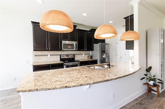 kitchen with light stone countertops, hanging light fixtures, stainless steel appliances, and sink