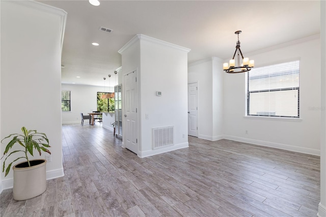 spare room featuring light hardwood / wood-style floors, ornamental molding, and an inviting chandelier