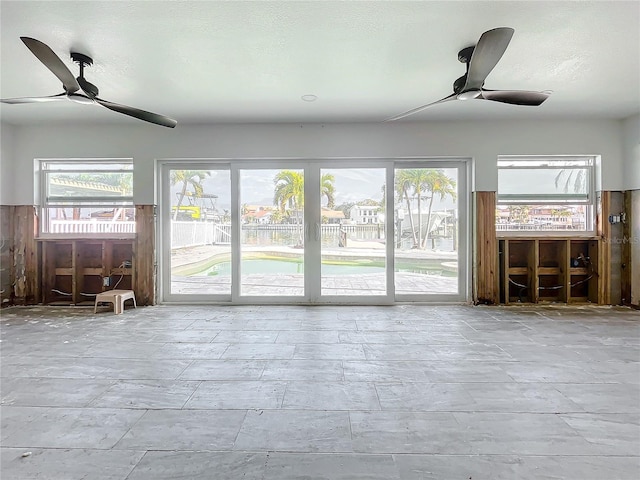 unfurnished living room with a wealth of natural light and ceiling fan