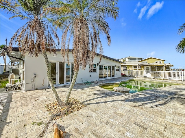 back of property with a patio and a fenced in pool