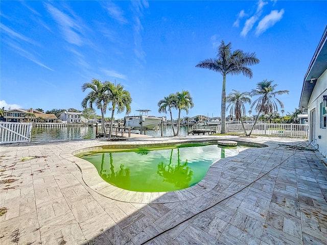 view of swimming pool with a dock, a water view, and a patio