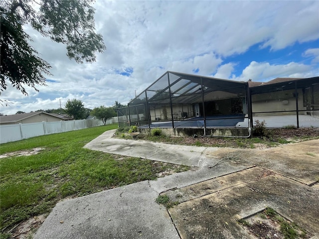 back of property featuring glass enclosure and a yard