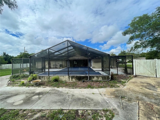 back of house featuring a pool and glass enclosure