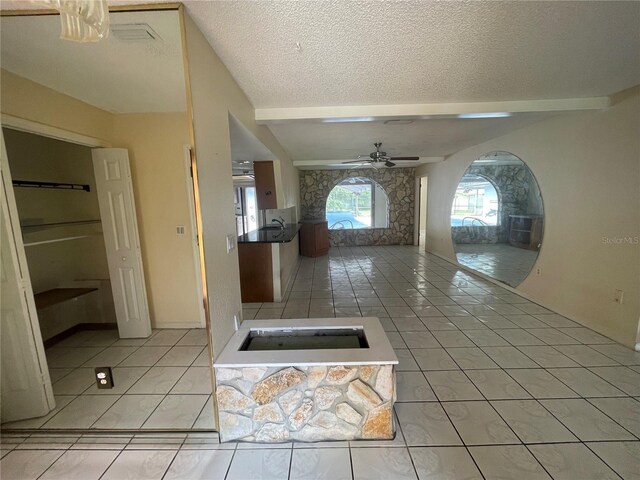 hall with beam ceiling, light tile patterned floors, and a textured ceiling