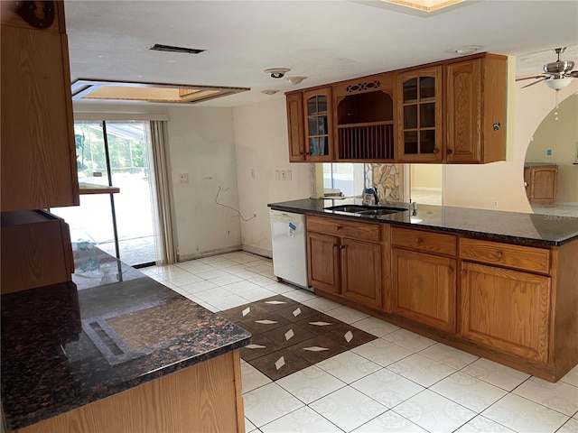 kitchen featuring ceiling fan, sink, kitchen peninsula, dark stone countertops, and white dishwasher