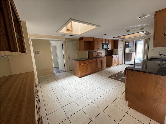 kitchen with kitchen peninsula, a skylight, and sink