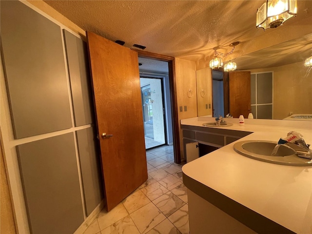 kitchen with a textured ceiling, kitchen peninsula, sink, and hanging light fixtures