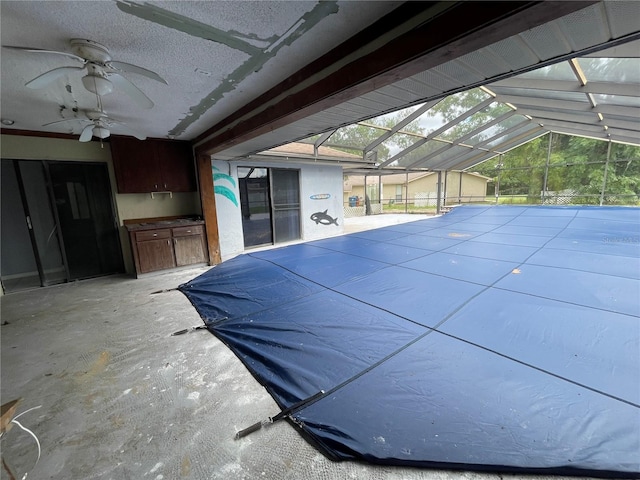 view of swimming pool featuring ceiling fan, a patio area, and glass enclosure