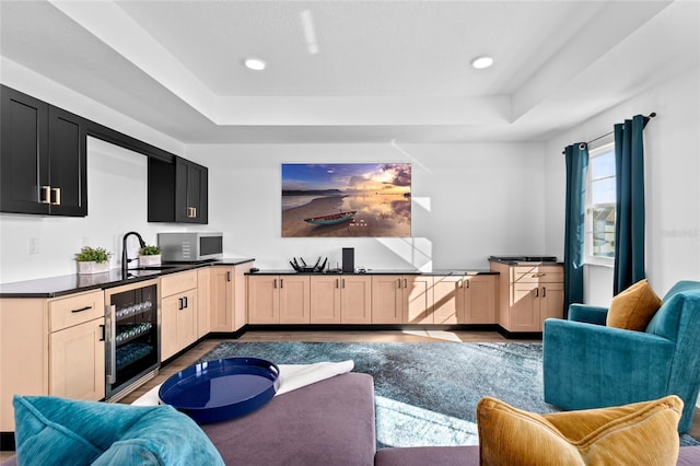 living room featuring a raised ceiling, sink, and beverage cooler