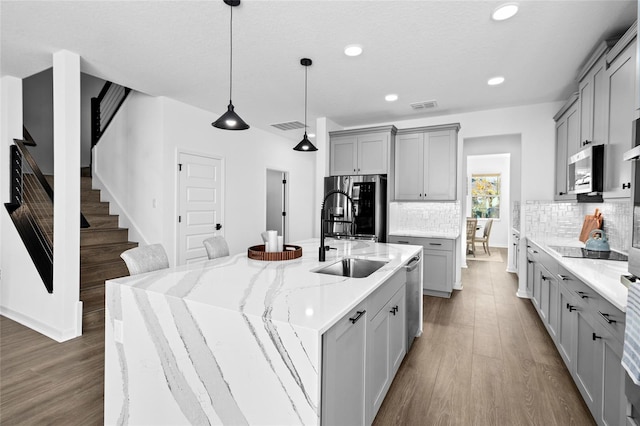 kitchen with tasteful backsplash, gray cabinetry, a large island, and stainless steel appliances