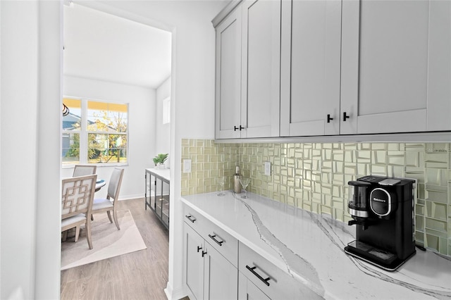 kitchen with decorative backsplash, light hardwood / wood-style flooring, and light stone countertops