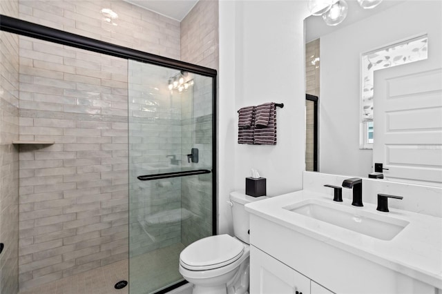 bathroom featuring vanity, a shower with shower door, and toilet