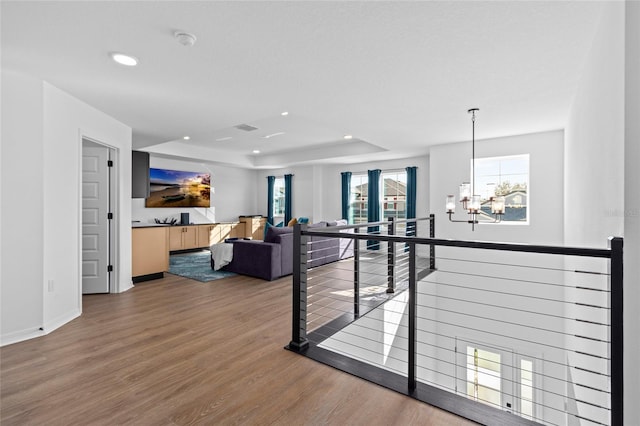 living room featuring hardwood / wood-style flooring, a notable chandelier, and a tray ceiling