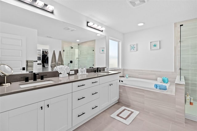 bathroom with tile patterned flooring, vanity, and plus walk in shower