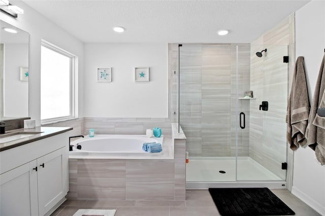 bathroom with tile patterned flooring, a textured ceiling, vanity, and plus walk in shower