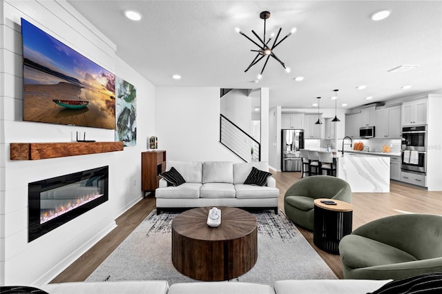 living room featuring hardwood / wood-style flooring, an inviting chandelier, and sink