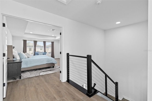 bedroom featuring light hardwood / wood-style floors and a tray ceiling