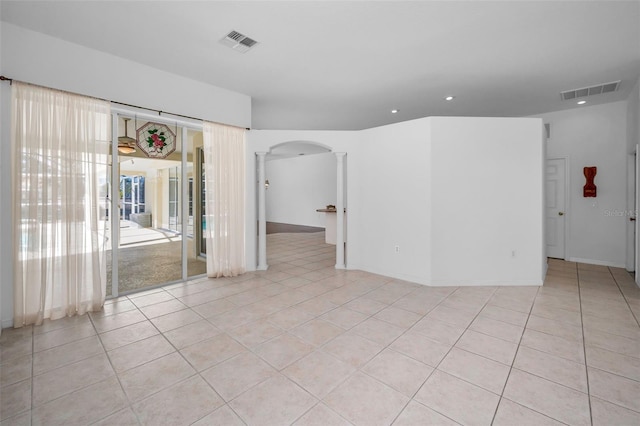 spare room with light tile patterned floors, decorative columns, and plenty of natural light