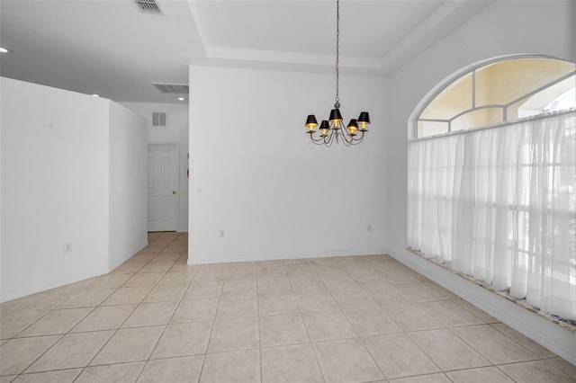 tiled empty room with a tray ceiling and an inviting chandelier