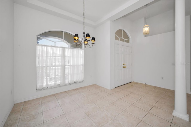 unfurnished dining area featuring ornate columns, light tile patterned floors, and a chandelier