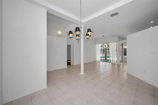 tiled spare room featuring an inviting chandelier