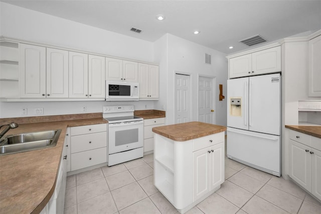 kitchen with white cabinetry, sink, light tile patterned floors, white appliances, and a kitchen island