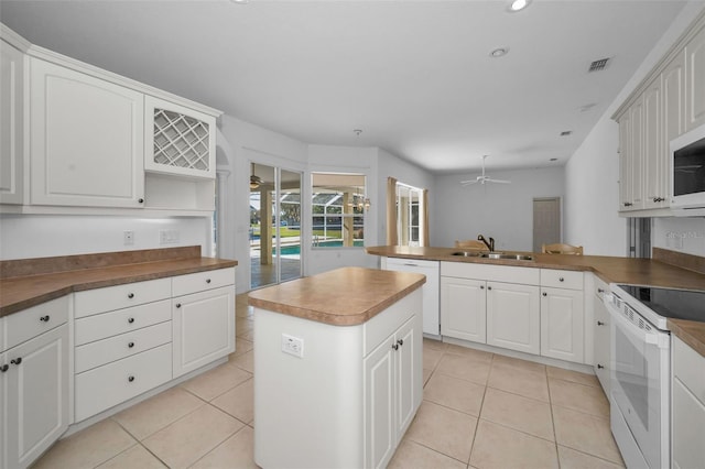 kitchen with white cabinetry, sink, a center island, ceiling fan, and white appliances