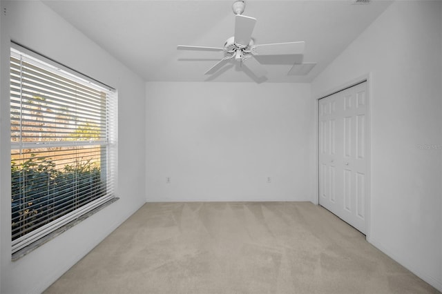 unfurnished bedroom featuring ceiling fan, a closet, and light carpet