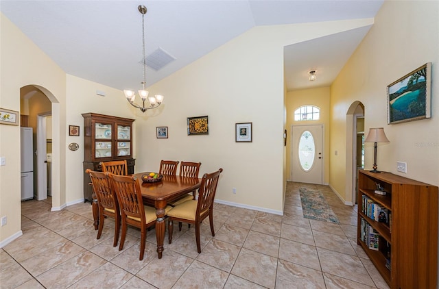 tiled dining room with lofted ceiling and an inviting chandelier