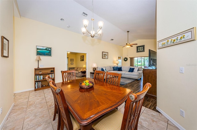 dining space with light tile patterned floors, ceiling fan with notable chandelier, and vaulted ceiling