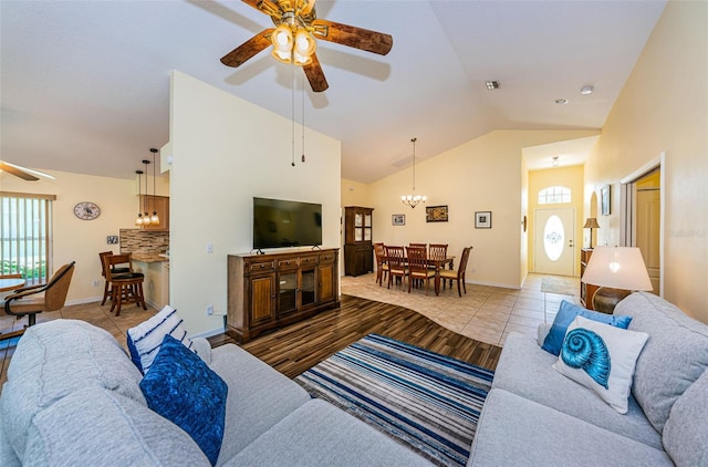 living room featuring light tile patterned floors, ceiling fan with notable chandelier, and vaulted ceiling