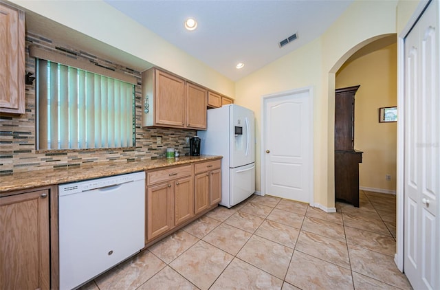 kitchen featuring light stone counters, vaulted ceiling, white appliances, decorative backsplash, and light tile patterned floors