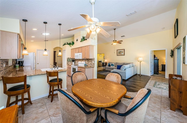 tiled dining space with a textured ceiling, vaulted ceiling, ceiling fan, and sink