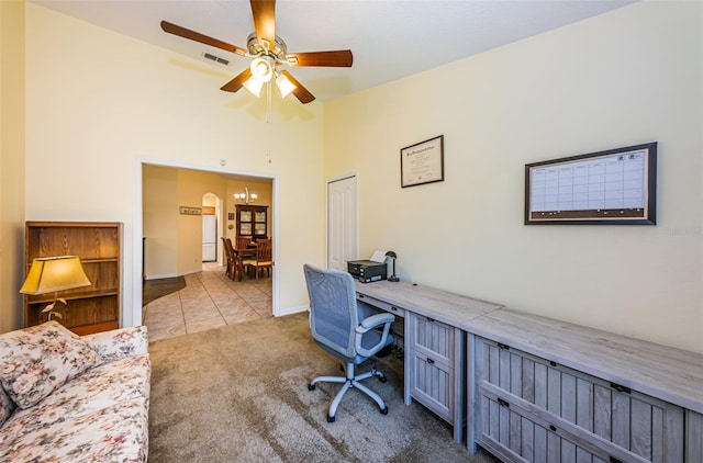 carpeted office space featuring ceiling fan with notable chandelier