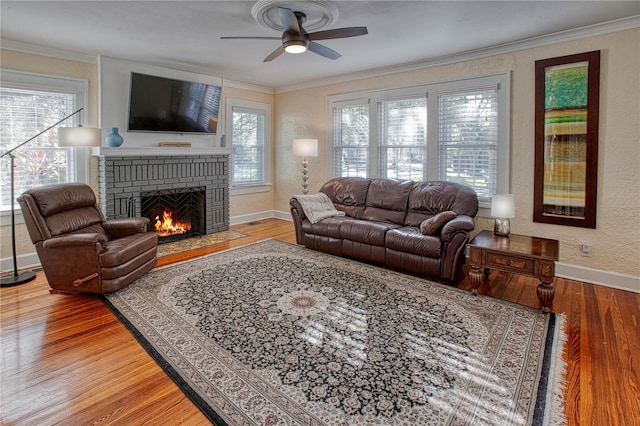 living room featuring hardwood / wood-style floors, ceiling fan, crown molding, and a fireplace