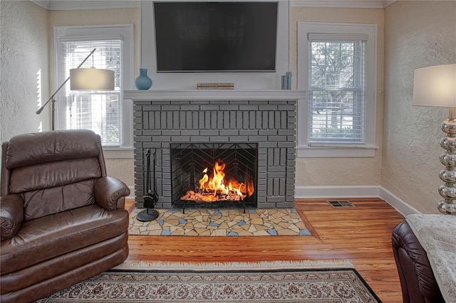 living room with a fireplace, hardwood / wood-style flooring, a wealth of natural light, and crown molding