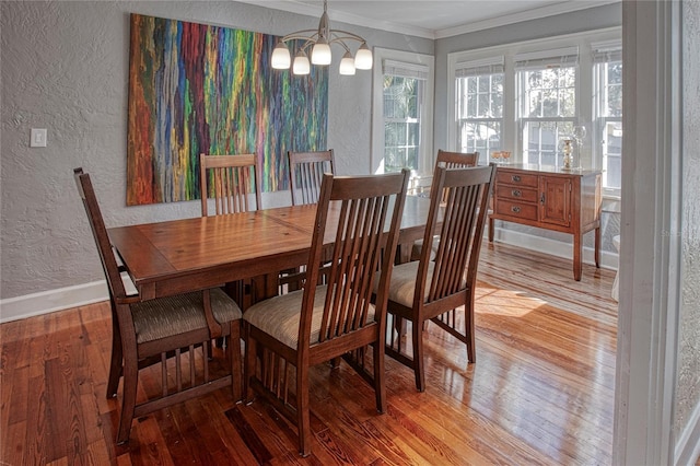 dining area with light hardwood / wood-style floors, a chandelier, and ornamental molding