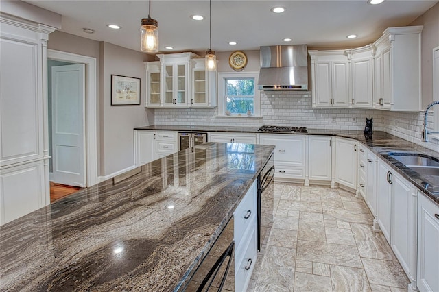 kitchen featuring white cabinets, hanging light fixtures, dark stone countertops, and wall chimney range hood