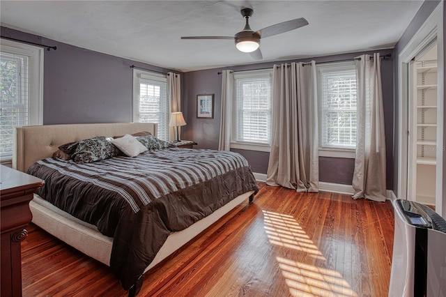 bedroom with multiple windows, ceiling fan, and dark wood-type flooring