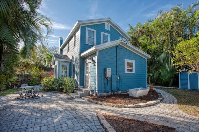 rear view of property with a shed and a patio