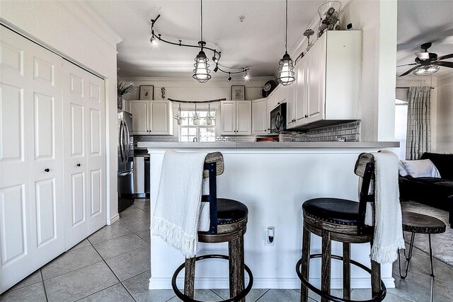 kitchen featuring a breakfast bar, white cabinetry, stainless steel fridge, hanging light fixtures, and kitchen peninsula