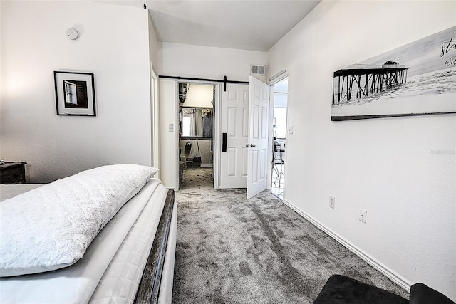 carpeted bedroom with a walk in closet and a barn door