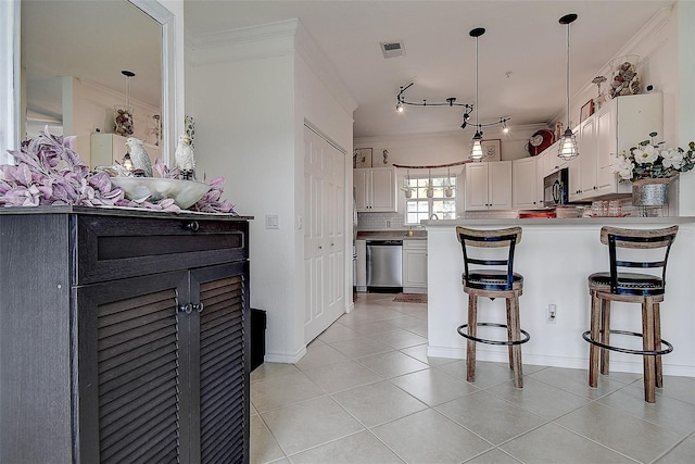 kitchen featuring white cabinetry, dishwasher, hanging light fixtures, ornamental molding, and kitchen peninsula