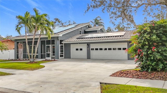 view of front of house featuring solar panels, a sunroom, and a garage