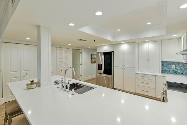 kitchen with white cabinets, a raised ceiling, stainless steel fridge with ice dispenser, and sink