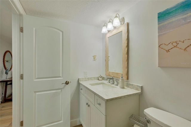 bathroom featuring vanity, a textured ceiling, and toilet