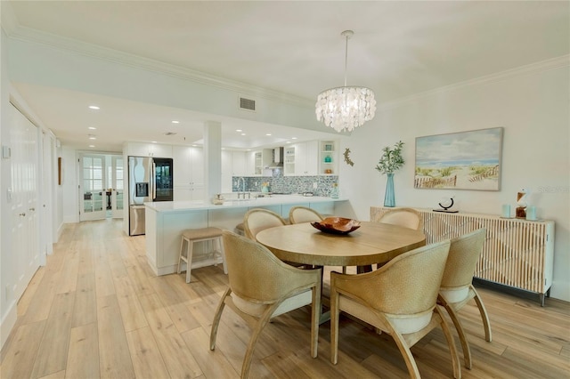 dining area with a chandelier, radiator heating unit, light hardwood / wood-style floors, and ornamental molding